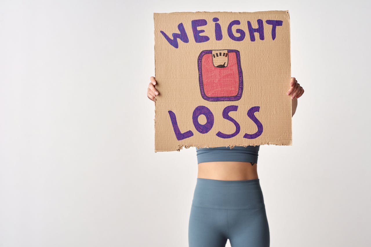 Person holding weight loss sign for fitness motivation and health goals.