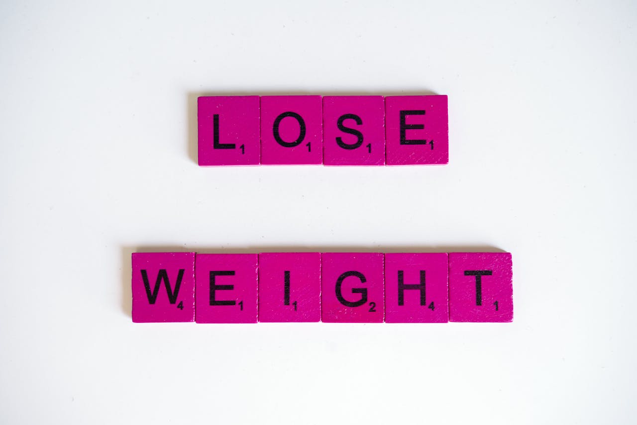 Creative image of the phrase Lose Weight spelled with Scrabble tiles on a white background.