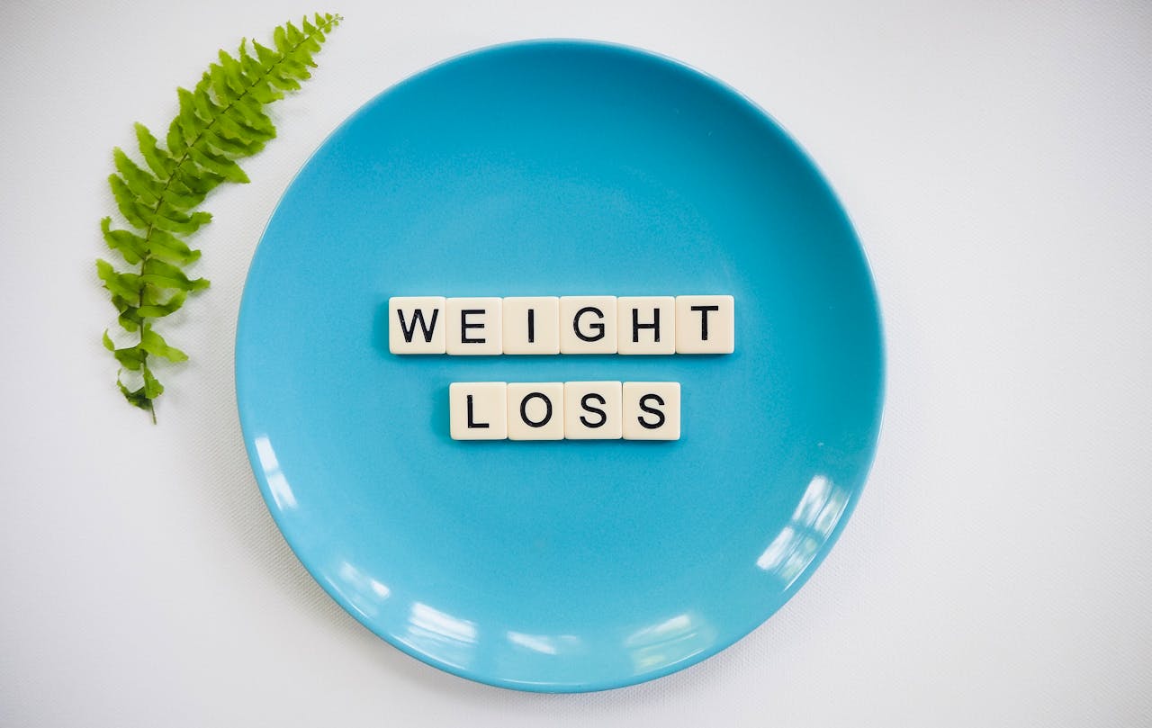 A blue plate with weight loss tiles and a fern leaf on white background.
